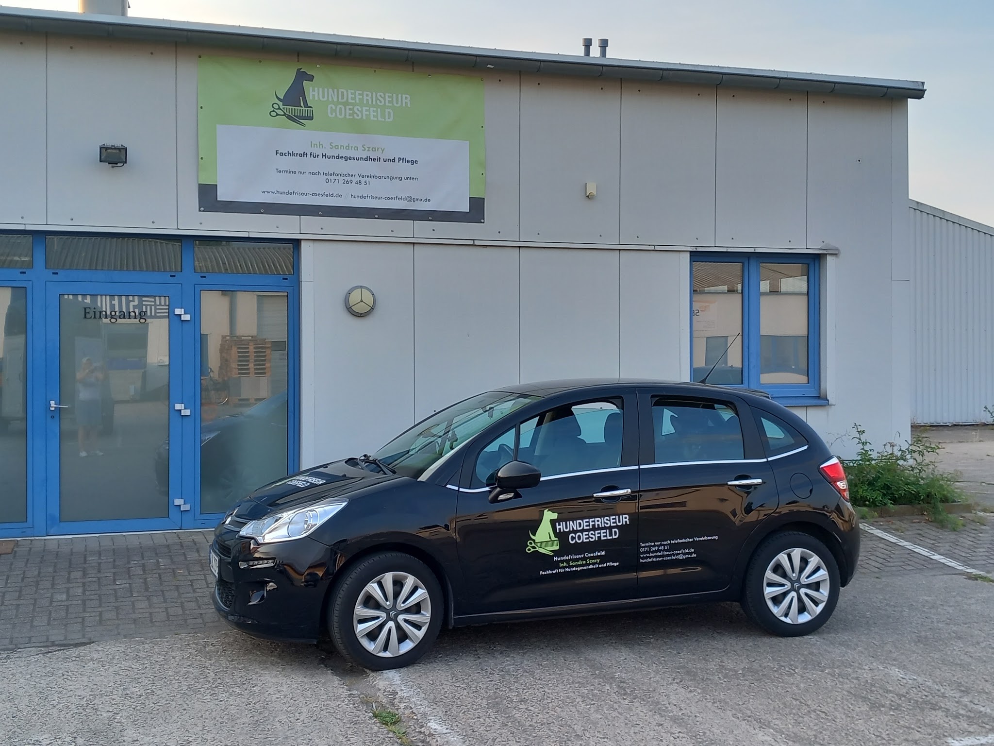 Außenansicht des Hundefriseur Coesfeld mit Logo-Banner und beschriftetem Fahrzeug